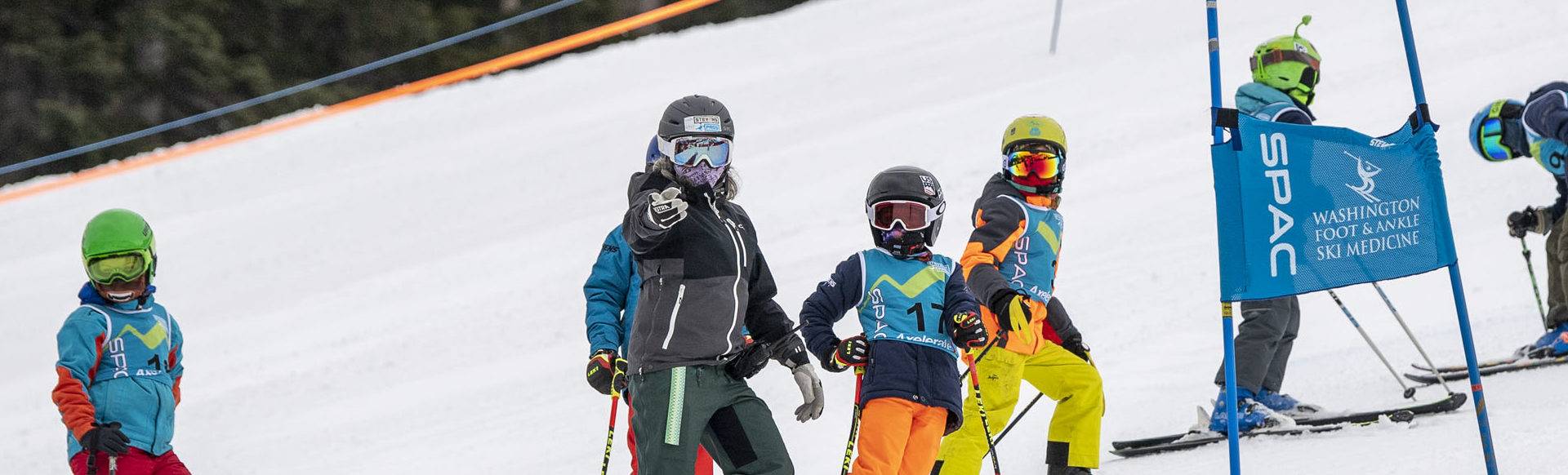 a coach directing children on a ski race course